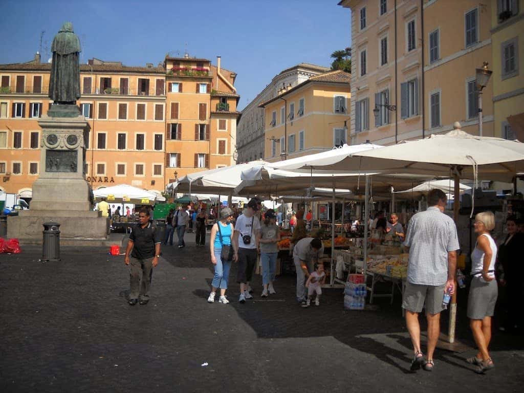 Market at Campo di Fiori with back of the statue of Giordano Bruno, a philosopher and mathematician, who was burned at the stake in the campo for heresy in 1600. 